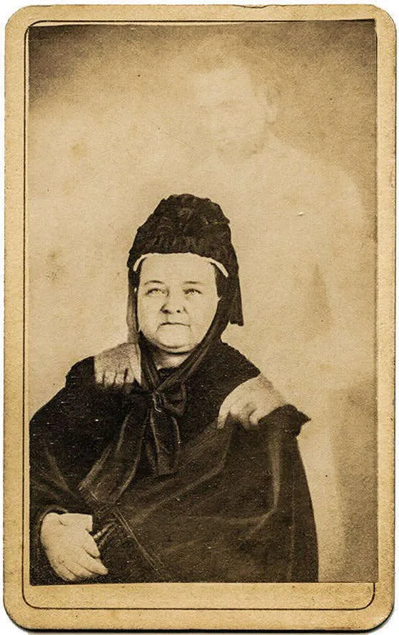 Carte de visite sépia, Mary Todd Lincoln assise en habit de deuil, silhouette pâle d'Abraham Lincoln derrière elle.